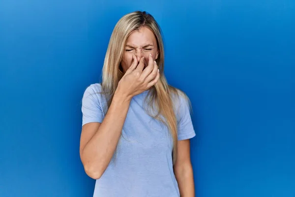 Beautiful Blonde Woman Wearing Casual Shirt Blue Background Smelling Something — ストック写真