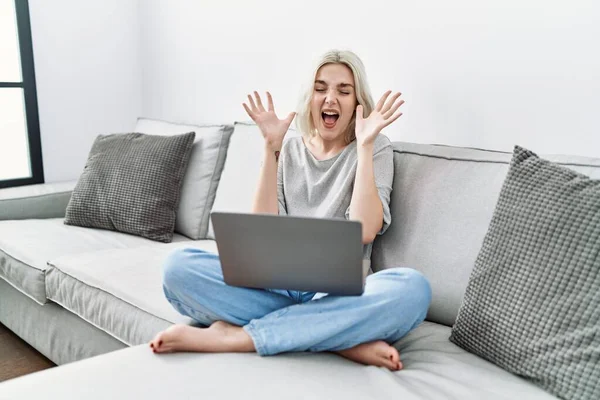 Young Caucasian Woman Using Laptop Home Sitting Sofa Celebrating Mad — Fotografia de Stock