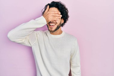 Yakışıklı, beyaz süveter giyen, gülümseyen ve gülen, gözlerini kapatan yakışıklı bir İspanyol. kör kavram. 