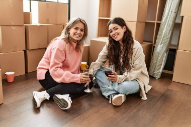 Gülümseyen genç çift yeni evinde kırmızı şarapla kadeh kaldırıyor.