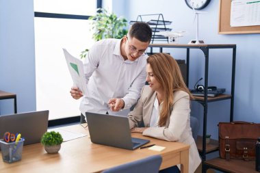 Kadın ve erkek işçiler ofiste dizüstü bilgisayar kullanıyorlar.