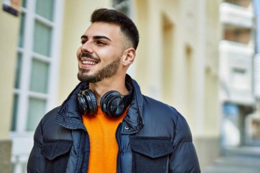 Yakışıklı, sakallı, neşeli ve kendine güvenen, kışlık palto giyen bir İspanyol.