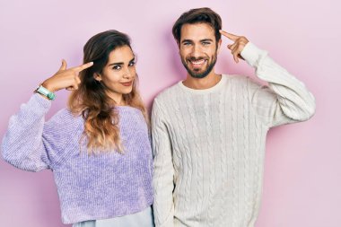 Gündelik kıyafetler giyen genç İspanyol çift iki eliyle başını işaret ediyor. Harika bir fikir ya da düşünce, iyi bir hafıza. 