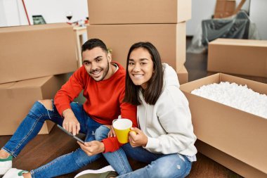 Genç Latin çift kahve içiyor ve yeni evlerinde dokunmatik ped kullanıyor..