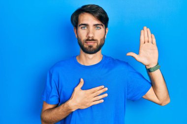 Latin asıllı genç adam, gündelik giysiler giyip, el pençe divan yemin ederek sadakat yemini ediyor. 