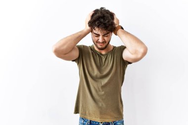 Hispanic man standing over isolated white background suffering from headache desperate and stressed because pain and migraine. hands on head. 