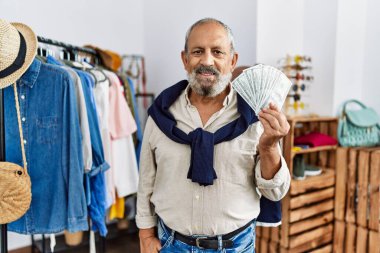 Perakende dükkanında elinde dolarlarla yakışıklı bir adam. Olumlu ve mutlu görünüyor. Kendine güvenen bir gülümsemeyle dişlerini gösteriyor. 