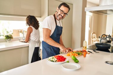 Orta yaşlı İspanyol çift mutfakta kendine güvenen yemekler pişiriyor.