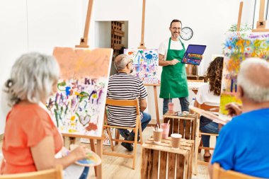 Bir grup orta yaşlı öğrenci resim stüdyosunda resim dersi alıyor..