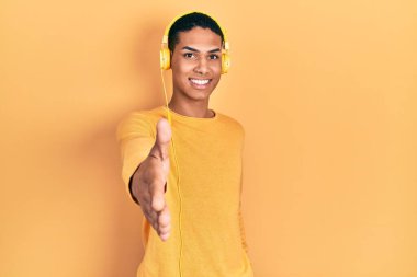 Genç Afro-Amerikalı adam kulaklık takarak müzik dinliyor. Gülümsüyor, avuç içi kadar yardım ve kabul görüyor.. 