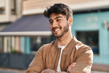 Genç İspanyol adam gülümsüyor. Kendine güveni tam. Sokakta çapraz hareketlerle duruyor.