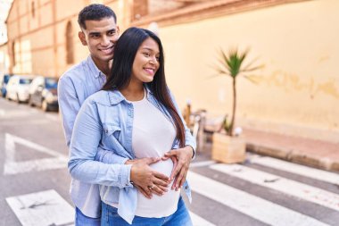 Latin bir çift bebek bekliyor. Sokakta birbirlerine sarılıyorlar.