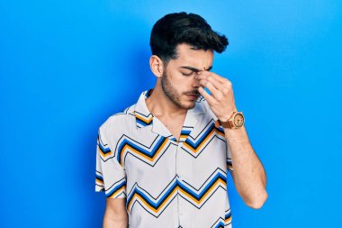 Günlük kıyafetler giyen genç İspanyol adam yorgun burnu ve gözleri ovuşturup yorgun ve baş ağrısı çekiyor. Stres ve hüsran kavramı. 