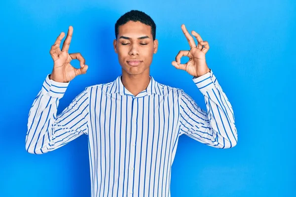 Young african american guy wearing casual clothes relax and smiling with eyes closed doing meditation gesture with fingers. yoga concept.