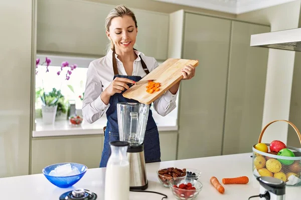 Young Blonde Woman Smiling Confident Pouring Carrot Blender Kitchen — Foto Stock