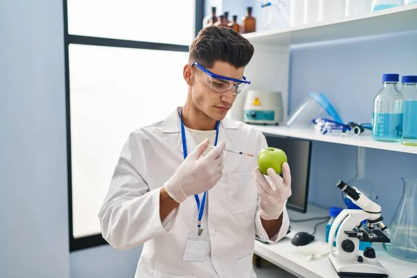 Young Hispanic Man Wearing Scientist Uniform Injecting Apple Laboratory — 图库照片