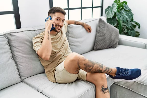 Jonge Spaanse Man Glimlacht Zelfverzekerd Aan Telefoon Thuis — Stockfoto