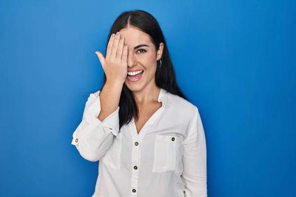 Mujer Hispana Joven Pie Sobre Fondo Azul Cubriendo Ojo Con —  Fotos de Stock