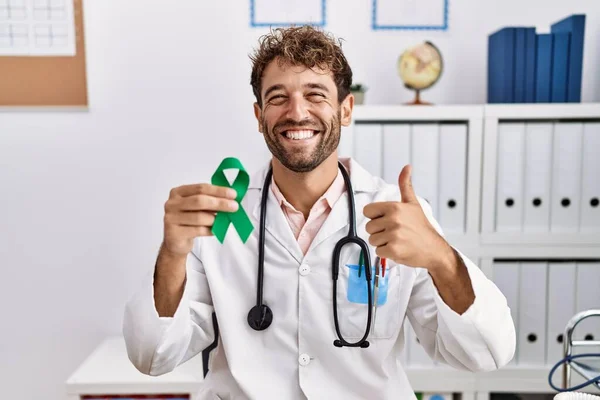 Joven Médico Hispano Sosteniendo Cinta Verde Apoyo Clínica Sonriendo Feliz — Foto de Stock