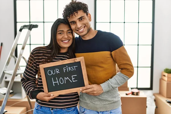 Young Latin Couple Smiling Happy Holding Our First Home Blackboard — стоковое фото