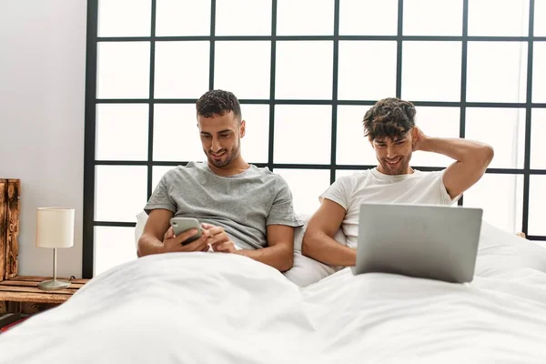 Two Hispanic Men Couple Using Laptop Smartphone Sitting Bed Bedroom — Stock Photo, Image