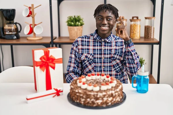 非洲男人拿着大巧克力蛋糕庆祝生日 手指点点地提出了一个成功的主意 又兴奋又快乐第一大 — 图库照片
