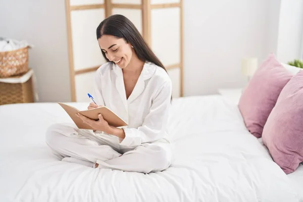 Young Hispanic Woman Writing Notebook Sitting Bed Bedroom — Fotografia de Stock