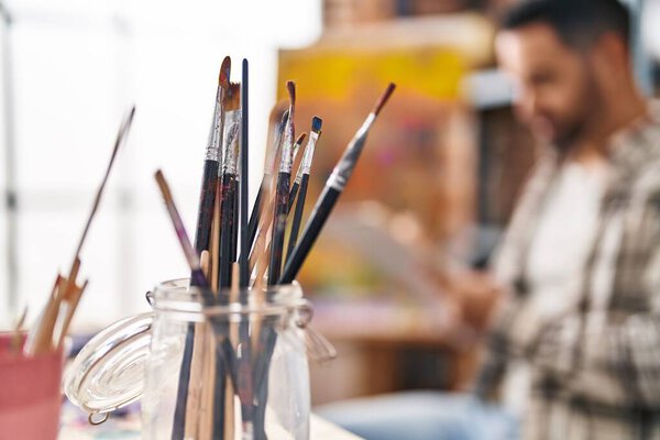 Young hispanic man drawing on notebook at art studio