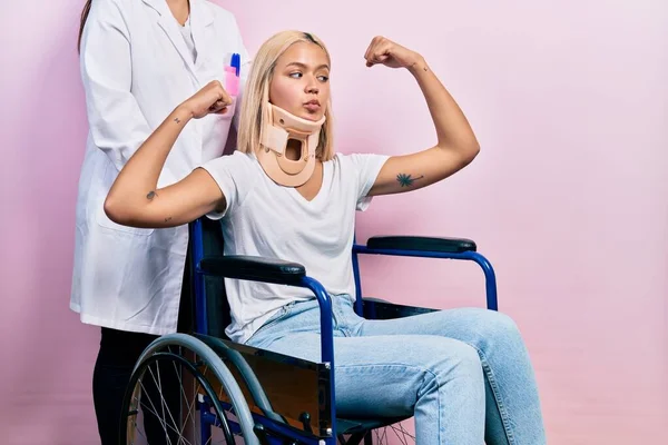 Beautiful blonde woman sitting on wheelchair with collar neck showing arms muscles smiling proud. fitness concept.