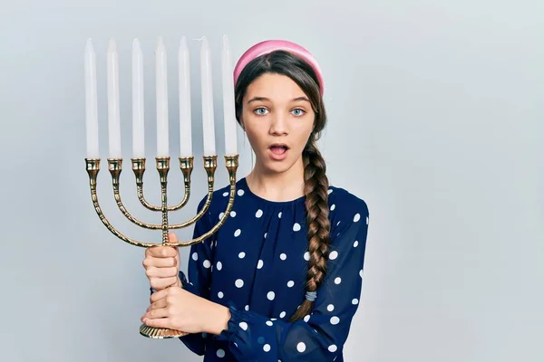 Young Brunette Girl Holding Menorah Hanukkah Jewish Candle Afraid Shocked —  Fotos de Stock