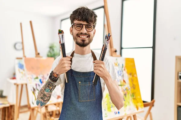 Joven Artista Hispano Sonriendo Feliz Sosteniendo Pinceles Estudio Arte — Foto de Stock