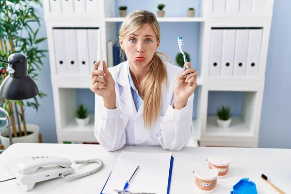 Beautiful Dentist Woman Holding Ordinary Toothbrush Electric Toothbrush Depressed Worry — 스톡 사진