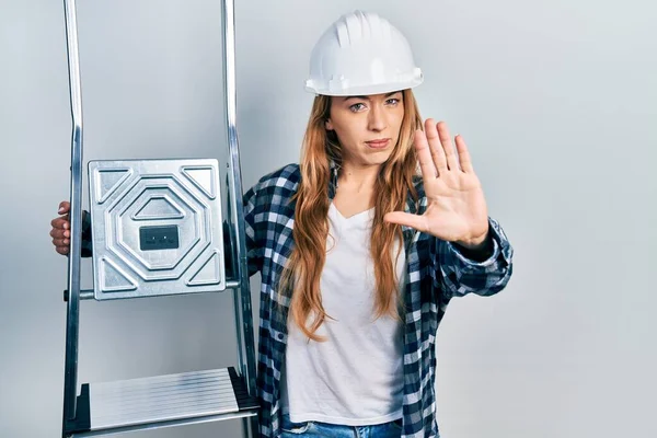 Jovem Mulher Caucasiana Vestindo Hardhat Segurando Escada Com Mão Aberta — Fotografia de Stock