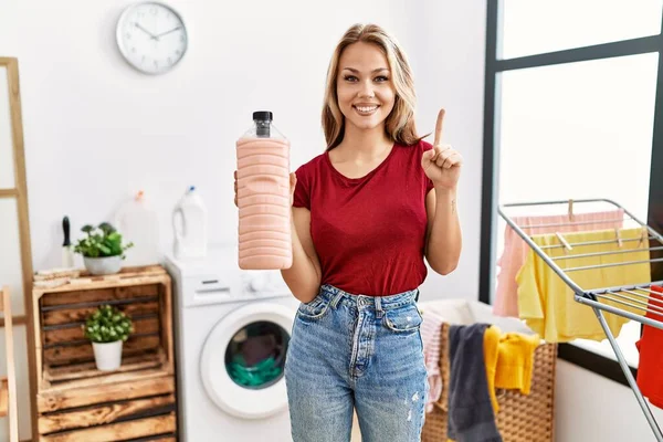 Young Caucasian Woman Holding Detergent Bottle Laundry Room Smiling Idea — Stok fotoğraf