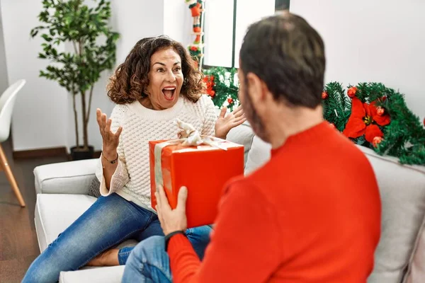 Hispanisches Paar Mittleren Alters Hält Weihnachtsgeschenk Hause Auf Dem Sofa — Stockfoto