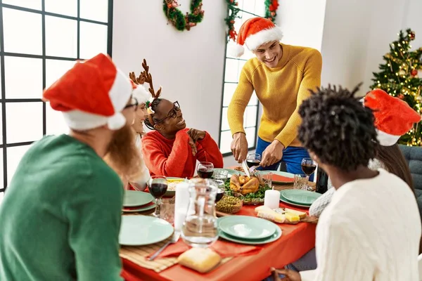 若い人たちのグループは 幸せなクリスマスディナーを持って笑って 男は自宅で提供するロースト七面鳥を切断 — ストック写真