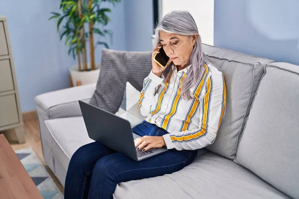 Middle Age Grey Haired Woman Using Laptop Talking Smartphone Home — Stock fotografie