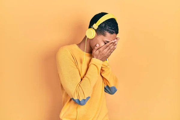 年轻的非洲裔美国人一边哭泣一边用带悲伤表情的耳机一边听音乐 抑郁症的概念 — 图库照片