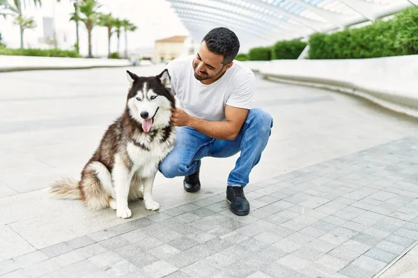 Young hispanic man smiling confident standing with dog at street