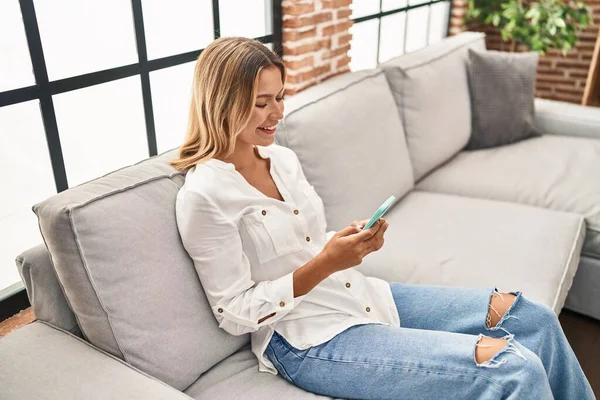 Junge Hispanische Frau Sitzt Mit Smartphone Hause Auf Sofa — Stockfoto