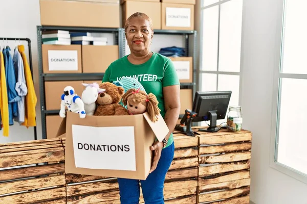Senior African American Woman Wearing Volunteer Uniform Holding Toys Donations — Stock Photo, Image