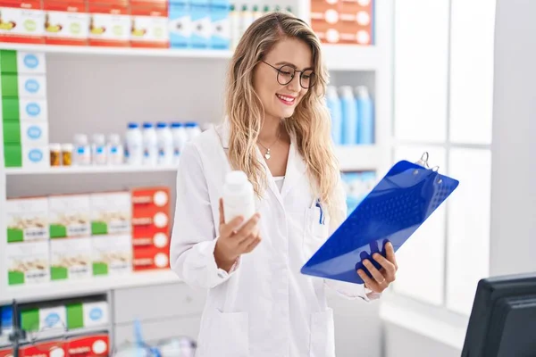 Young Woman Pharmacist Reading Report Holding Pills Bottle Pharmacy — ストック写真