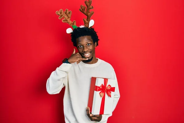 Jovem Afro Americano Usando Chapéu Natal Veado Segurando Presente Sorrindo — Fotografia de Stock