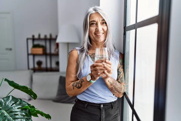 中年白髪の女性笑顔自信に満ちた飲料水に家 — ストック写真