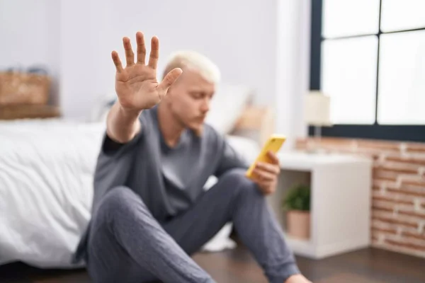 Young Caucasian Man Using Smartphone Doing Stop Gesture Hand Bedroom — Stok fotoğraf