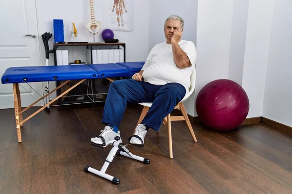 Senior Caucasian Man Physiotherapy Clinic Using Pedal Exerciser Looking Stressed — Fotografia de Stock