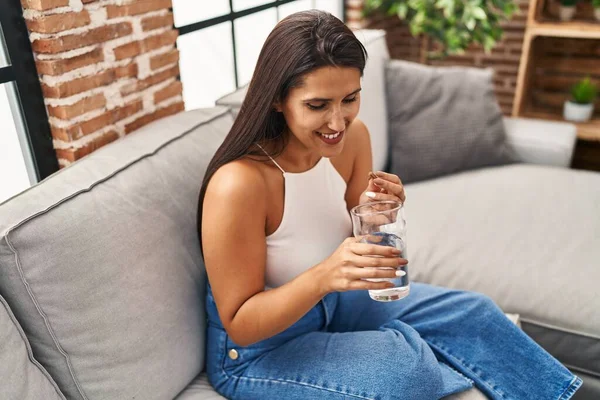 Ung Latinamerikansk Kvinna Tar Piller Dricksvatten Sitter Soffan Hemma — Stockfoto