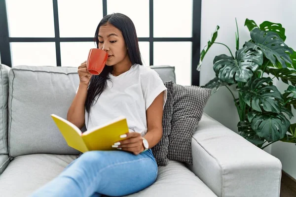 Νεαρή Λατίνα Γυναίκα Πίνει Καφέ Διαβάζοντας Βιβλίο Στο Σπίτι — Φωτογραφία Αρχείου