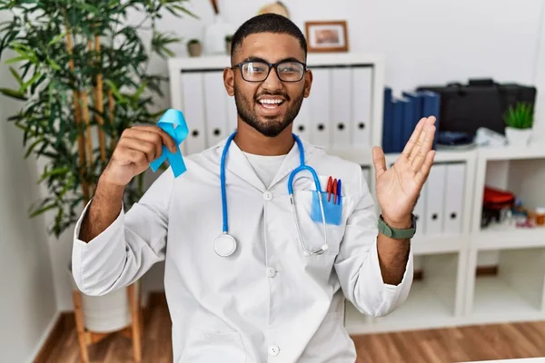 Young Indian Doctor Holding Blue Ribbon Celebrating Victory Happy Smile — Stock Photo, Image