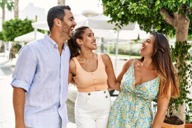 Üç İspanyol arkadaş şehirde mutlu bir şekilde gülüyor ve sarılıyorlar..